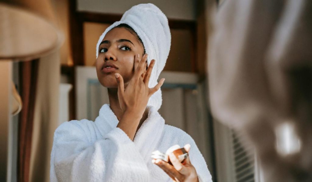 Mujer aplicando crema facial en rutina skincare para una piel luminosa