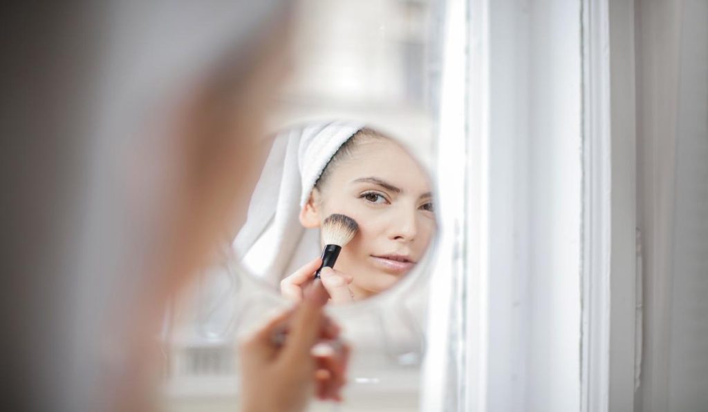Mujer preparando la piel antes de aplicar los polvos de maquillaje