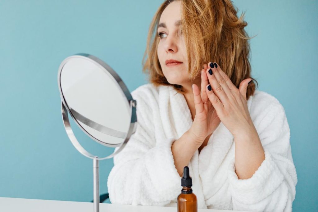 Mujer observando su cabello frente al espejo preocupada por la caída del cabello