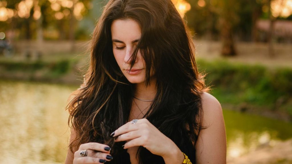 Mujer revisando su cabello durante un periodo de estrés o preocupación