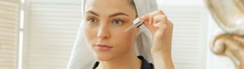 Mujer aplicando sérum facial con retinoides en su rutina de cuidado de la piel