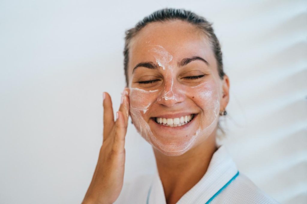 Mujer aplicando crema de protección solar en el rostro