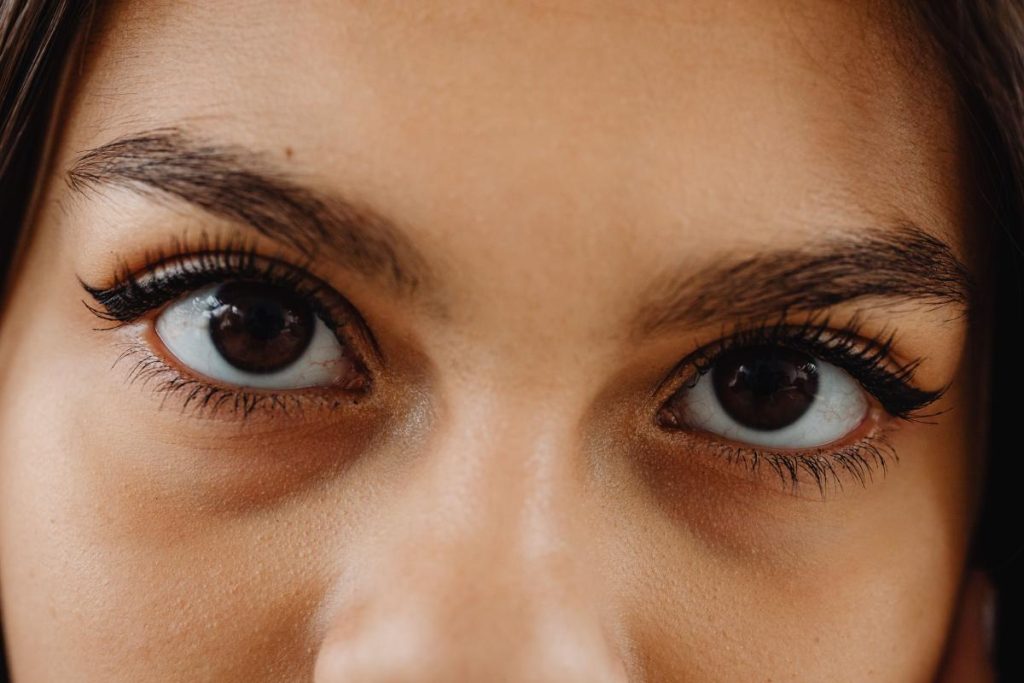 Primer plano de una mujer con zonas oscuras bajo los ojos y maquillaje en las pestañas.