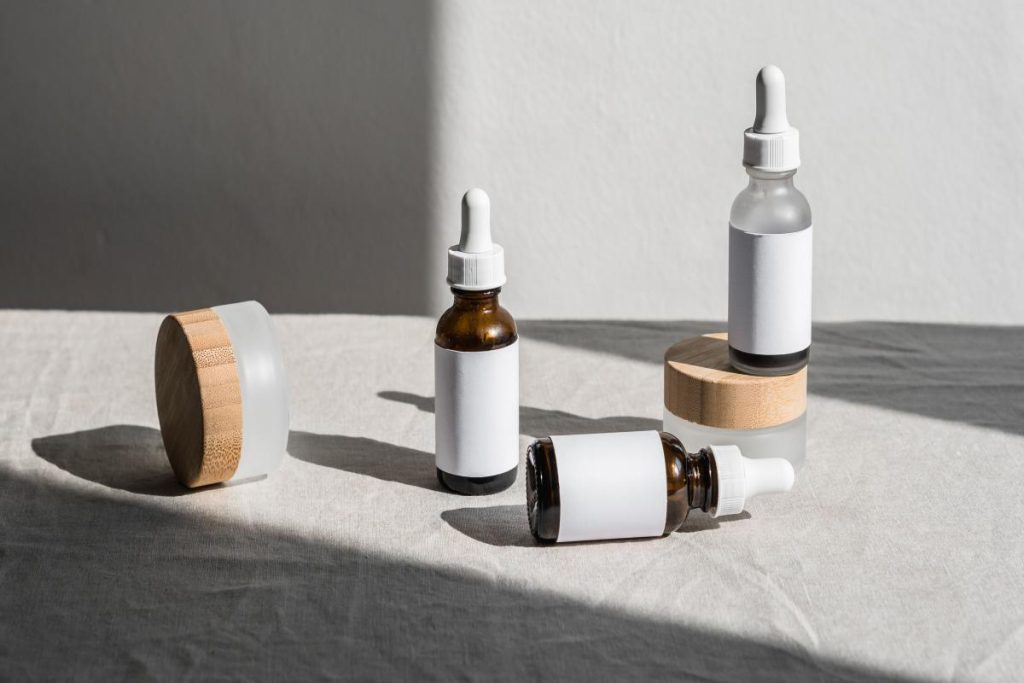 Mujer con una espátula de crema junto a la mejilla y fondo antracita. Imagen destacada del artículo de MujerGlobal sobre cómo combinar retinol y niacinamida en la rutina facial.
