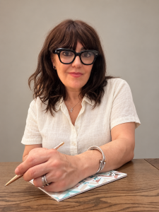 Sonia Gil, fundadora de MujerGlobal, con camisa blanca y un bolígrafo sobre un cuaderno.